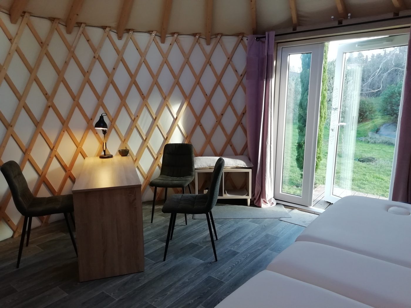 Intérieur de la yourte : espace d'accueil et baie vitrée ouverte sur le jardin
